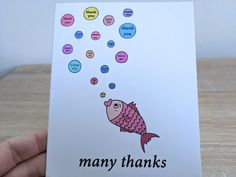 a hand holding up a card that says many thanks with a fish and bubbles coming out of it