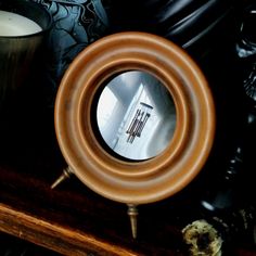 a mirror sitting on top of a wooden table next to a candle and other items