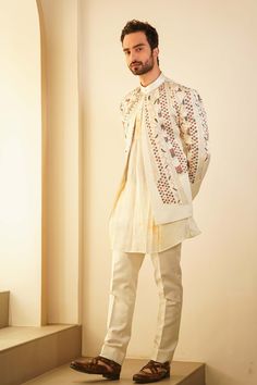 Editor's Note Featuring Our Bestseller Short Jacket, Now In A Dirty Ivory Color. Paired With A Champagne Marble Dyed Kurta And Tapered Trousers, Is Our Four Level-paneled Hand Embroidered Short Jacket Set, Inspired By Pablo Picasso's Cubism Artwork. Fabric: Linen Silk Color: Ivory Component: Short Jacket, Kurta. Trousers Care: Dry Clean Only About the Designer After establishing himself as the leading couturier in the industry of menswear, Jatin Malik went on to explore luxury footwear. You can Beige Long Sleeve Bandhgala With Chikankari Embroidery, Festive White Outerwear With Chikankari Embroidery, Designer Long Sleeve Bandhgala For Spring, Fitted White Sherwani For Spring, White Long Sleeve Bandhgala For Spring, White Fitted Sherwani For Spring, Traditional White Sets With Set-in Sleeves, Festive White Outerwear With Resham Embroidery, White Sets For Fall Wedding