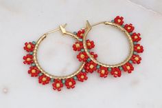 Add a touch of whimsical charm to your spring and summer wardrobe with these beautiful hand-beaded gold filled hoop earrings. Each earring is meticulously beaded with delica seed beads in a delightful flower pattern resembling daisies, making them perfect for a fun and playful look.  The vibrant red hues add a pop of color to any outfit, making these earrings a must-have accessory for the season. Stand out in style with these charming and unique hoop earrings that are sure to brighten up your da Red Bohemian Jewelry For Spring, Bohemian Hoop Earrings For Spring Gift, Handmade Small Hoop Earrings For Spring, Bohemian Hoop Earrings As Spring Gift, Handmade Hoop Earrings For Spring, Summer Hoop Earrings With Tiny Beads For Gift, Handmade Bohemian Hoop Earrings For Spring, Flower Shaped Hoop Earrings For Summer, Bohemian Handmade Hoop Earrings For Spring