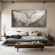 a large painting hanging above a bed in a room with white walls and flooring