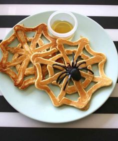 a spiderweb pancake on a plate next to two forks and a knife