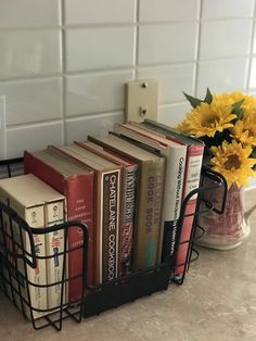 a bunch of books that are sitting on a counter next to a vase with flowers