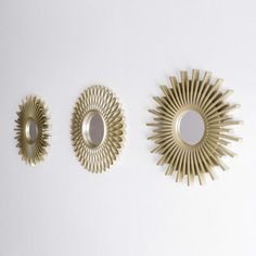 three mirrors are arranged on the wall in different shapes and sizes, each with an individual's own sunburst