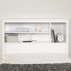 a white bed with a book shelf above it