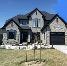 a house that is in the middle of a yard with grass and rocks around it