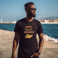 Crafted with care, these Cruise Tees are designed to celebrate Black culture, individuality, and wanderlust. With a sleek black background, these shirts feature stunning, vibrant artwork that pays tribute to Black women and men, capturing the essence of travel and exploration. Whether you're setting sail on the high seas or embarking on a journey to new horizons, our Dope Black Cruise Shirts make the perfect Travel Day Outfit. Their unique designs and premium quality ensure you'll stand out in a crowd while staying comfortable throughout your entire vacation. These Black Girl Outfits and Black Man shirts are more than just apparel; they're a statement of pride and a symbol of unity. Let your fashion speak for itself as you express your love for travel and embrace your cultural heritage.Don Black Graphic Tee For Vacation, Black Graphic Print Shirt For Vacation, Black Graphic Print Vacation Top, Black Graphic Print Top For Vacation, Black Text Print T-shirt For Vacation, Black Text Print Top For Vacation, Black Text Print Tops For Vacation, Travel Day Outfit, Man Travel