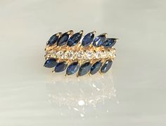 A glamorous and noticeable vintage sapphire ring featuring 12 marquise cut blue sapphires uniquely set on an angle while separated by a row of sparkling white diamonds weighing 0.50 carats, set in solid 14k yellow gold. *Ring size: US 6 1/2 *Ring weight: 7.14 grams *Complimentary resizing is available up to 3 sizes larger or smaller than stated size. Vintage Blue Marquise Sapphire Ring, Marquise Ring Vintage, Dainty Earrings Studs, Antique Emerald Ring, Women 90s, Sapphire And Diamond Band, Vintage Sapphire Ring, Emerald Ring Vintage, Marquise Ring