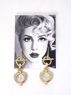 Introducing the stunning Gold Crystal Studded Heart Shape Quartz Watch Clock Statement Earrings - the ultimate combination of luxury and uniqueness! These earrings feature fully functional glass dial watches with gold crystals, adding a touch of elegance to your outfit. Their medium weight allows for comfortable wear, making them the perfect accessory for any occasion. Elevate your style and make a chic statement with these stunning earrings. Product Details.Fully functional glass dial Quartz wa Advertising And Promotion, Stunning Earrings, Quartz Watch, Statement Jewelry, Statement Earrings, Bridesmaid Gifts, Jewelry Shop, Semi Precious, Heart Shapes