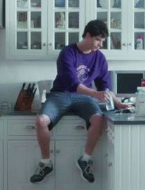 a young man sitting on top of a kitchen counter