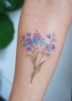 a small blue flower tattoo on the arm