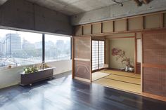 an empty room with large windows and wood flooring in front of a bathtub