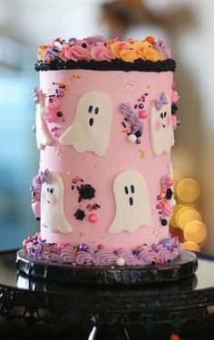 a pink cake with ghost decorations on it