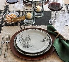 the table is set with plates, silverware and wine glasses