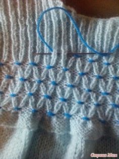 a close up of a knitted piece of cloth with blue yarn on it and the stitchs being sewn together