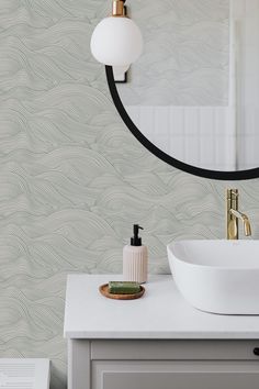 a white sink sitting under a bathroom mirror next to a wall mounted faucet