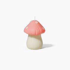 a pink mushroom candle sitting on top of a white table