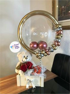 a teddy bear sitting on top of a table next to a balloon filled with pearls