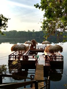 a dock with thatched umbrellas and chairs on it