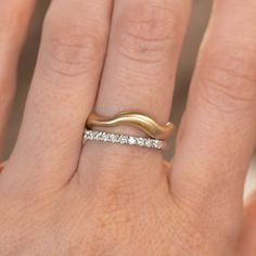 a woman's hand with a gold ring and diamond band