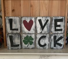 four wooden blocks with the words love, luck and shamrocks painted in black on them