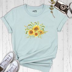 Introducing our Sunflower Shirt, the perfect addition to any floral lover's wardrobe! This beautiful tee features a stunning sunflower graphic that will brighten up your day and elevate any outfit. Made with high-quality materials, our Sunflower Shirt is soft, comfortable, and durable, making it the perfect everyday shirt. The floral design is not only trendy but also timeless, making it a great investment for your wardrobe. Our Sunflower Shirt is perfect for any occasion, whether you're running errands or going out with friends. Pair it with jeans and sneakers for a casual look, or dress it up with a skirt and heels for a night out. At our store, we prioritize customer satisfaction and quality products. We are confident that our Sunflower Shirt will exceed your expectations. It's also a g Summer Cotton Shirt With Plants Print, Blue Plant Print Summer Top, Blue Plant Print Top For Summer, Botanical Style Shirt With Relaxed Fit For Summer, Yellow Floral Print Relaxed Fit Shirt, Botanical Style Relaxed Fit Shirt For Summer, Yellow Floral Print Shirt With Relaxed Fit, Yellow Sunflower Print Summer Shirt, Summer Cotton T-shirt With Floral Print