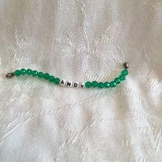 a green beaded bracelet with the word andy written on it and beads attached to it