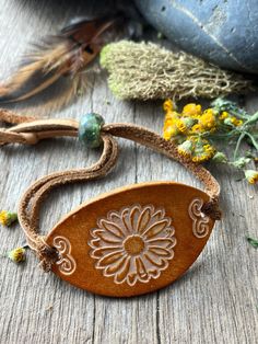 a wooden necklace with a flower on it sitting next to some flowers and other items