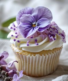 a cupcake with white frosting and purple flowers