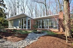 a modern house in the woods surrounded by trees and rocks, with large windows on each side