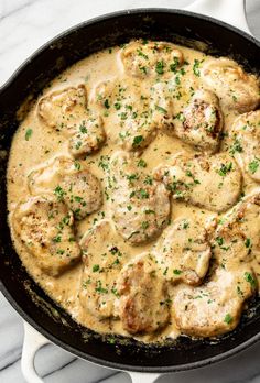 a skillet filled with meat and gravy on top of a white table