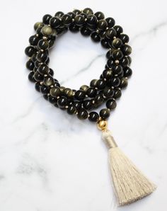 'I am empowered to pursue my passions.' Gold Sheen Obsidian, also known as the "wizard stone," has a long history of being used as a scrying mirror for divination and future prediction. Its reflective surface helps to bring clarity to the mind and alleviate confusion, allowing for deep introspection and personal growth. The reflective nature of Gold Sheen Obsidian has made it a popular tool for self-reflective meditation and fostering internal growth and understanding. Its properties also promot Fine Meaning, Internal Growth, Gold Sheen Obsidian, Scrying Mirror, Sheen Obsidian, Long History, The Wizard, Mala Necklace, Mala Beads