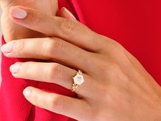 a woman's hand wearing a gold ring with an oval shaped diamond on it