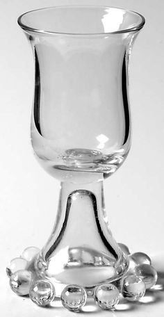 a clear glass vase sitting on top of a white table next to some silver balls