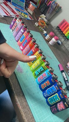 a person is pointing at the top of a row of colorful pencils on a table