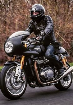 a man riding on the back of a black motorcycle down a curvy road