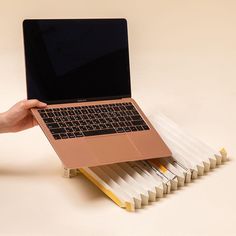 a hand is holding a laptop on top of several file folders that are stacked together