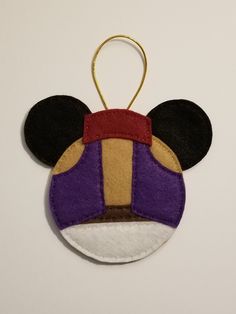 a mickey mouse ornament hanging on a white wall with a red, yellow and purple stripe