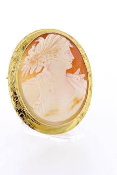 This delightful cameo brooch is made in 14K yellow gold and oval cut cut piece with a Greek motif with a female figure. She’s detailed with braided hair, feathers, and roses. The brooch is accented with an engraved bezel and migraine edge. It can also be worn as a necklace too—has a toggle that can flip up or down. The entire piece measures 57mm long, 46.31mm wide, 11.33mm tall, and weighs 10.7DWT.  B55KIPPN  --Please reference our policy for more details before purchase--***For International or Hair Feathers, Convertible Necklace, Carved Shell, Braided Hair, Gold Hand, Female Figure, Cameo Brooch, Gold Hands, Migraine