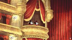 two mickey mouse heads are sitting on the top of a balcony in front of red drapes