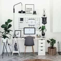 a white desk topped with a computer monitor next to a potted plant on top of a wooden floor