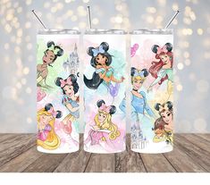 three disney princess tumblers sitting on top of a wooden table