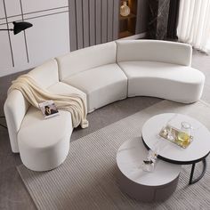 a white couch sitting on top of a living room floor next to a coffee table