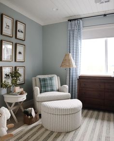 a baby's room with blue walls and striped rugs on the floor, white rocking chair