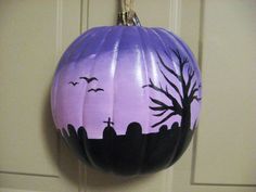 a painted pumpkin hanging from a hook in front of a door with bats on it