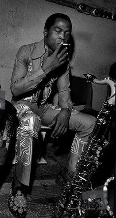 a black and white photo of a man playing the saxophone in front of other people