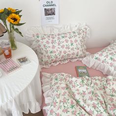 a bed with pink and white bedspread next to a vase filled with sunflowers