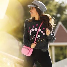 a woman is walking down the street with her pink handbag and smiling at someone