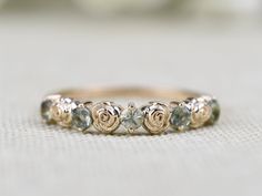 a close up of a ring on a white surface with flowers in the middle and two diamonds at the bottom