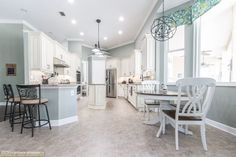 a large kitchen with white cabinets and counter tops next to a breakfast nook table